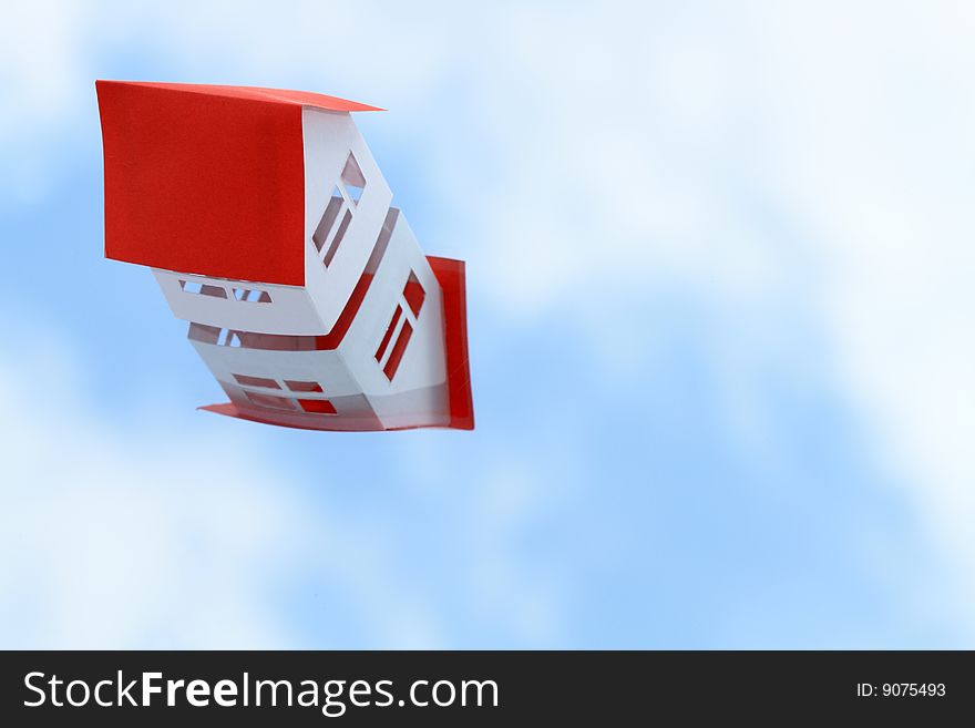 White paper house with red roof on blue sky background. White paper house with red roof on blue sky background