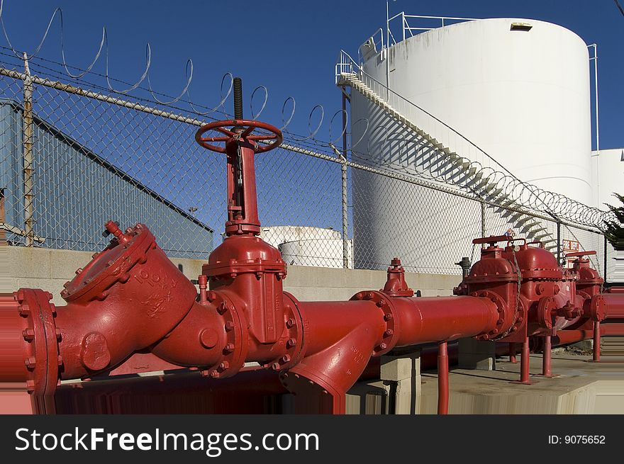 A chemical storage tank and large iron pipes are part of a liquid chemical storage facility. A chemical storage tank and large iron pipes are part of a liquid chemical storage facility.
