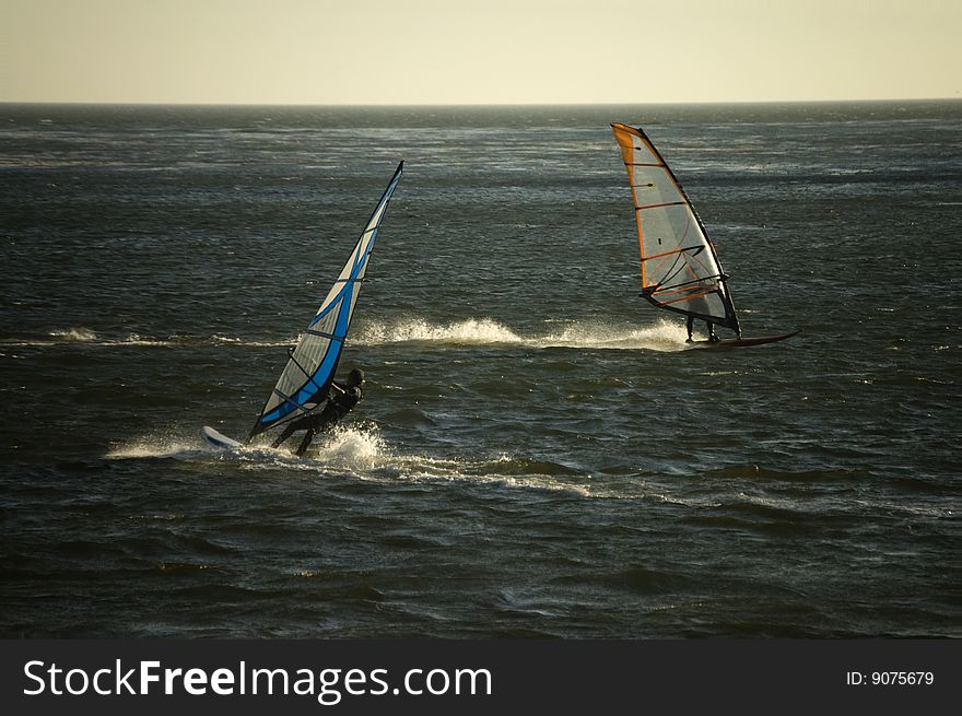 Two wind surfers cross paths in the ocean. Two wind surfers cross paths in the ocean.