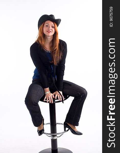 Young girl with  black hat sitting on chair on white background. Young girl with  black hat sitting on chair on white background