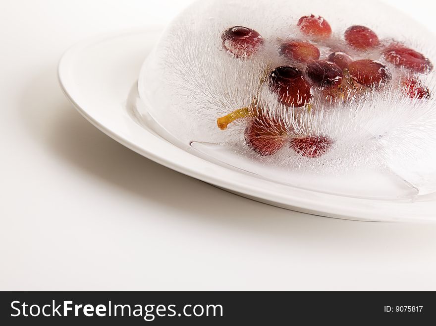 Grape fruit frozen in a ice block on a white plate. Grape fruit frozen in a ice block on a white plate