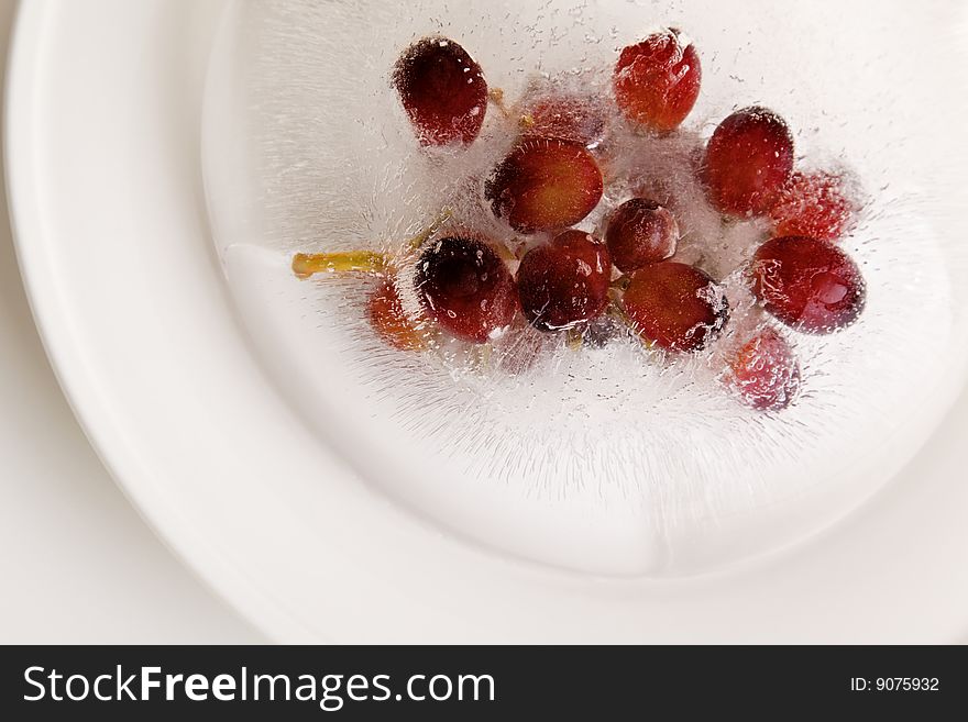 Grape fruit frozen in a ice block on a white plate. Grape fruit frozen in a ice block on a white plate