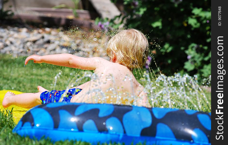 Young boy having fun splashing in water on a hot summer day. Young boy having fun splashing in water on a hot summer day