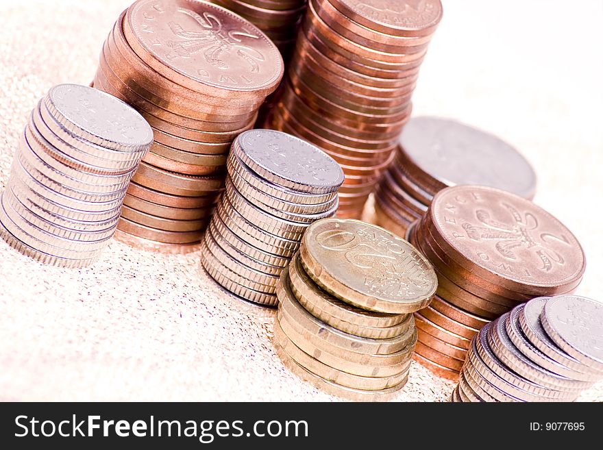 Piles of various coins arranged on gold backing. Piles of various coins arranged on gold backing