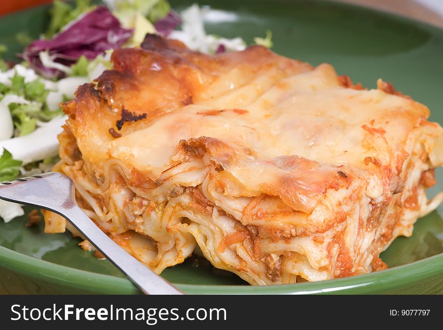 Meat lasagna with fresh salad on green plate. Meat lasagna with fresh salad on green plate