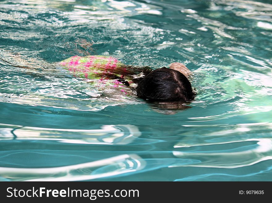 Little girl swimming  across the pool
