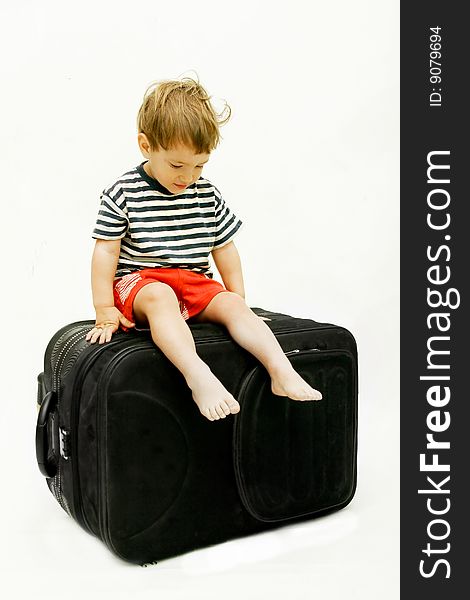 Young boy on big black suitcase