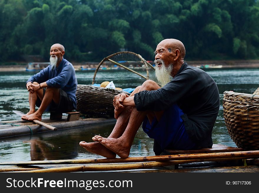 Two Men Sitting on Riverbank