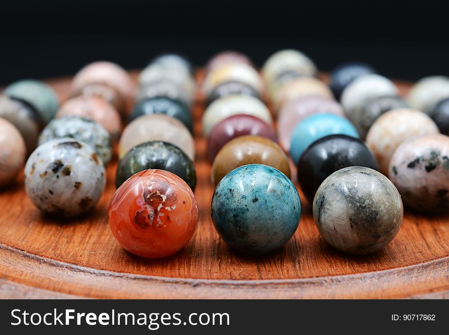 Close up of colorful marbles on wooden tray.