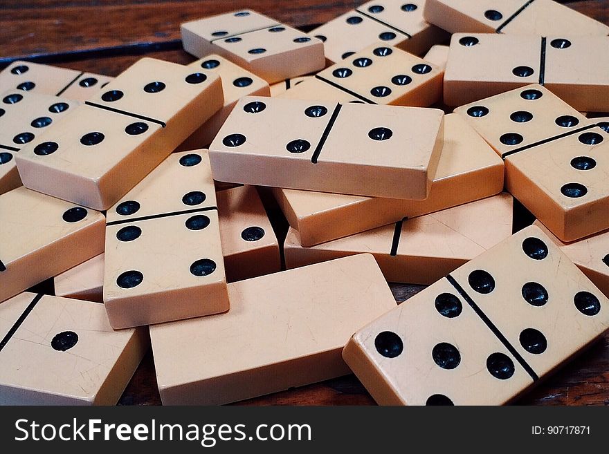Close up of dominoes in pile on wood.