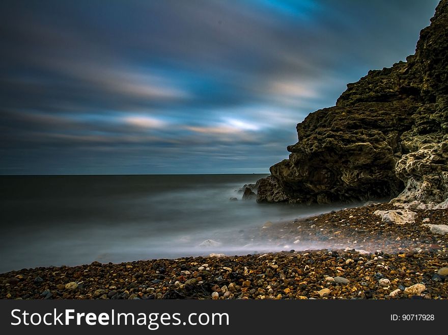 Rocky beach next to cliff along waterfront at sunset. Rocky beach next to cliff along waterfront at sunset.