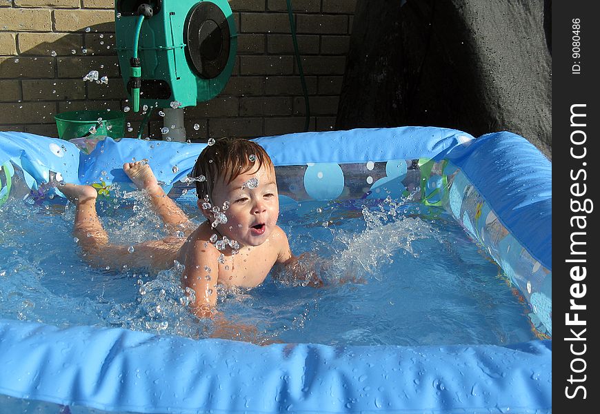 A male toddler diving into a paddling pool with water splashing up. A male toddler diving into a paddling pool with water splashing up.