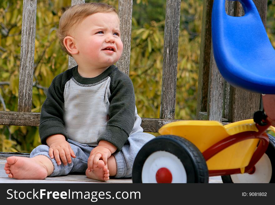 Cute little boy playing next to his tricycle