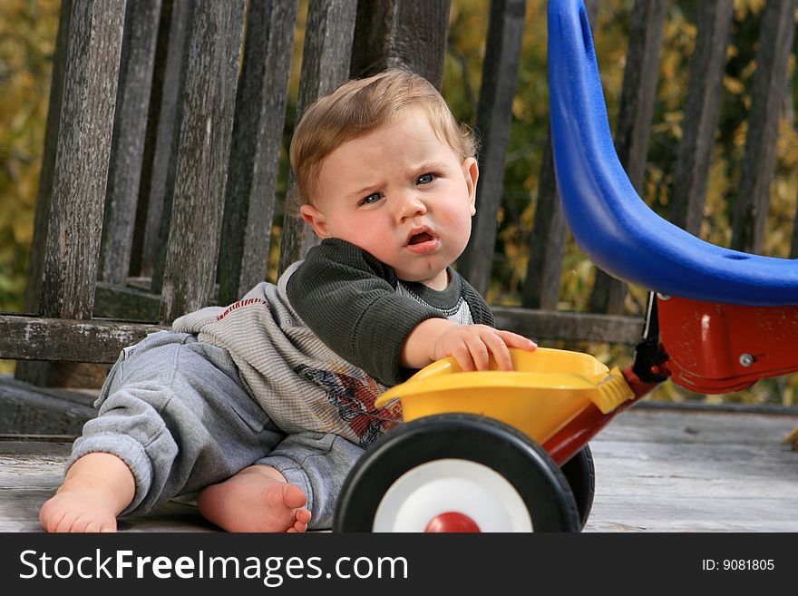 Cute little boy playing with his tricycle