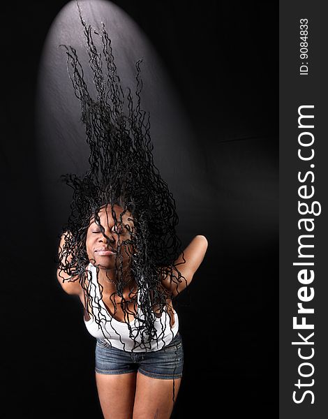 Wind - lovely young afro-american woman with long flapping hairs against black background