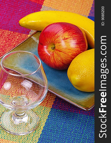 A glass and a plate of fruits on a colorful background. A glass and a plate of fruits on a colorful background