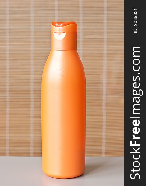 A plastic bottle of shampoo. Bamboo mat background out of focus.