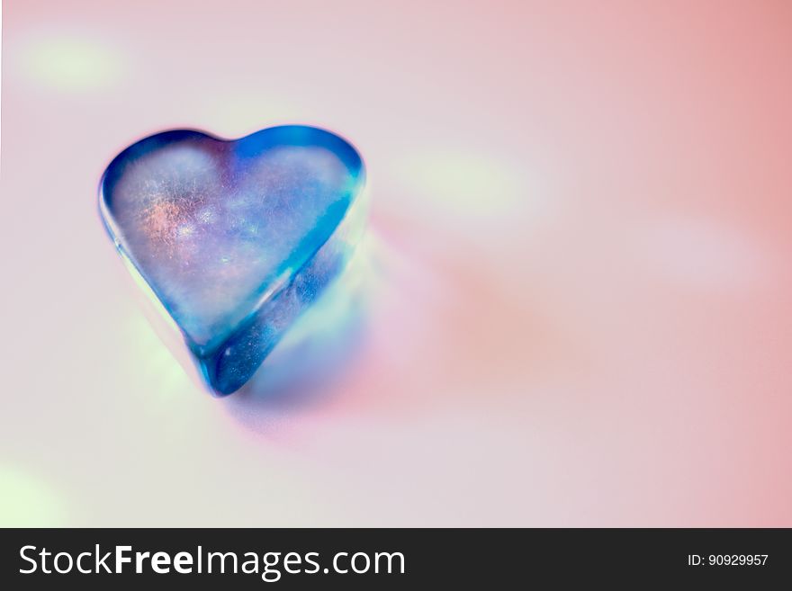 Close up of blue glass heart shaped ornament on pink. Close up of blue glass heart shaped ornament on pink.