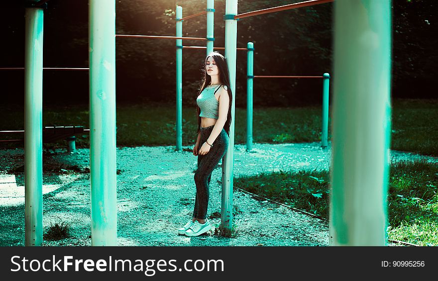 Portrait of young woman in blue jeans and grey top outdoors in jungle gym. Portrait of young woman in blue jeans and grey top outdoors in jungle gym.