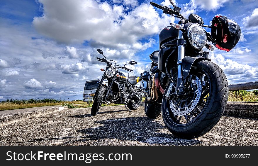 Motorcycles on road in countryside with blue skies and clouds.