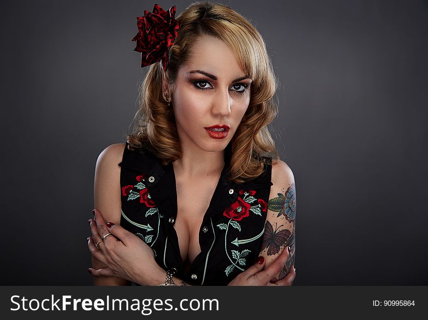 Woman in Black Red and Green Floral Sleeveless Shirt With Red Flower on Her Head and Butterfly Tattoo on Her Left Arm