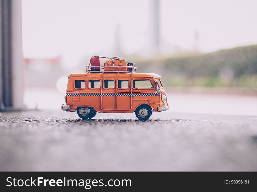 A close up of a toy minibus with luggage on the roof.