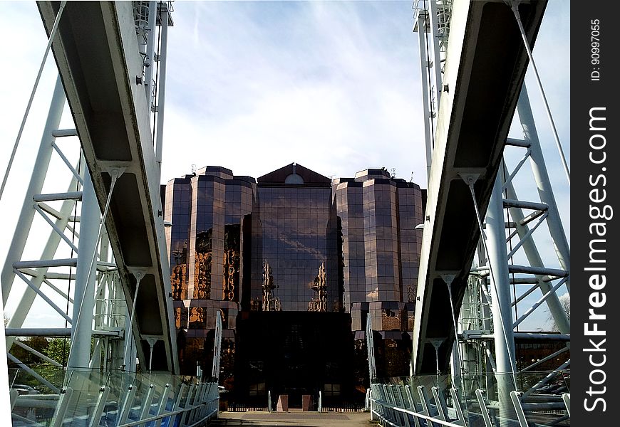 A view from a bridge at a building with reflective panels on the wall. A view from a bridge at a building with reflective panels on the wall.