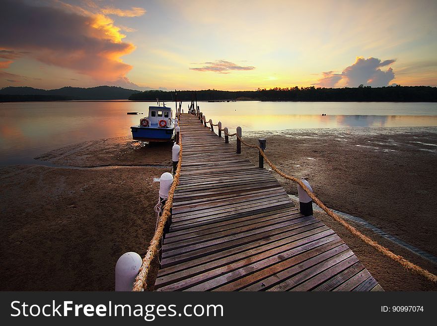 A wooden pier with boat docket at sunset. A wooden pier with boat docket at sunset.