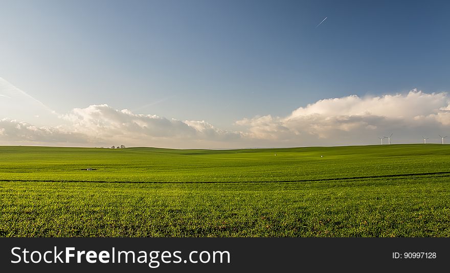 A landscape with green cultivated fields and blue skies above. A landscape with green cultivated fields and blue skies above.