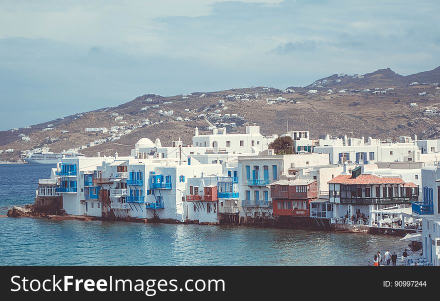 White houses along waterfront of Mykonos, Greece on sunny day.
