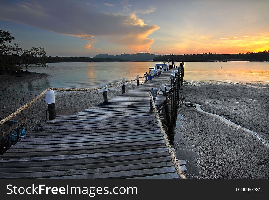 Wooden pier jetting into water along shores at sunset. Wooden pier jetting into water along shores at sunset.