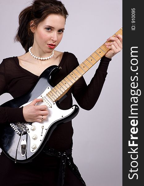 A Young woman playing an electric guitar, wearing black and looking straight at the camera. A Young woman playing an electric guitar, wearing black and looking straight at the camera