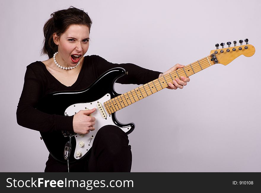 A young woman screaming as she holds an electric guitar. A young woman screaming as she holds an electric guitar
