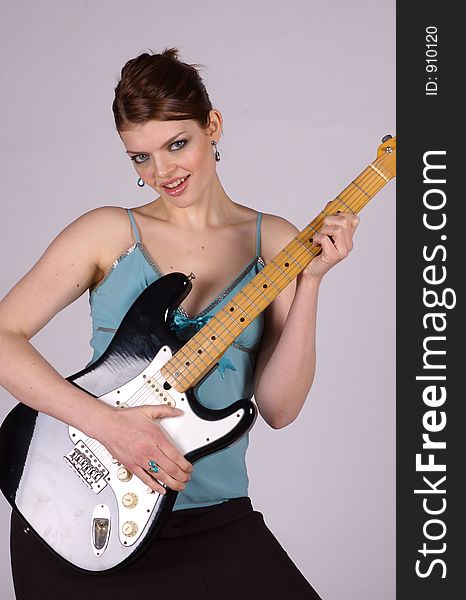 A Young woman holding an electric guitar, with a smile on her face. A Young woman holding an electric guitar, with a smile on her face