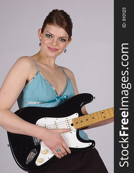 A young woman smiling and holding an electric guitar