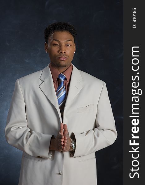 A man in a suit, posing with his hands together. A man in a suit, posing with his hands together