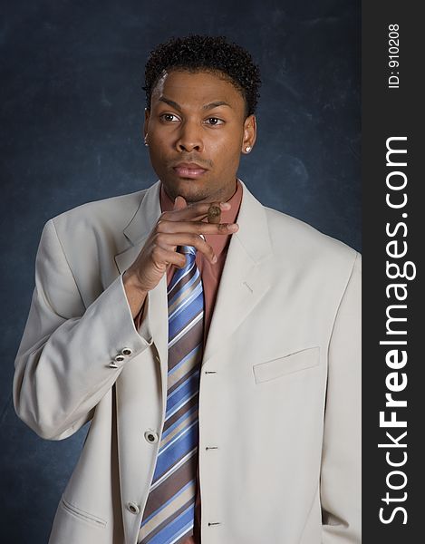 A man in a suit, holding a cigar with a look of deep thought on his face