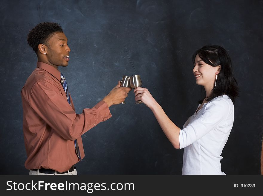 A man and woman toasting with two goblets, facing each other and smiling. A man and woman toasting with two goblets, facing each other and smiling