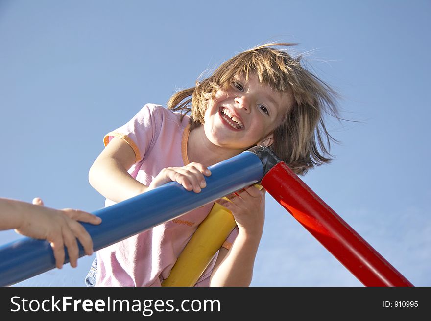 Young girl playing on a climbing pole - looking down to the photografer. Young girl playing on a climbing pole - looking down to the photografer