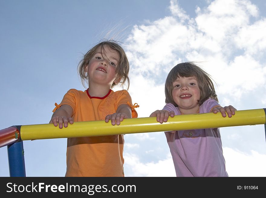 Twins on a climbing pole - looking down to the photografer. Twins on a climbing pole - looking down to the photografer