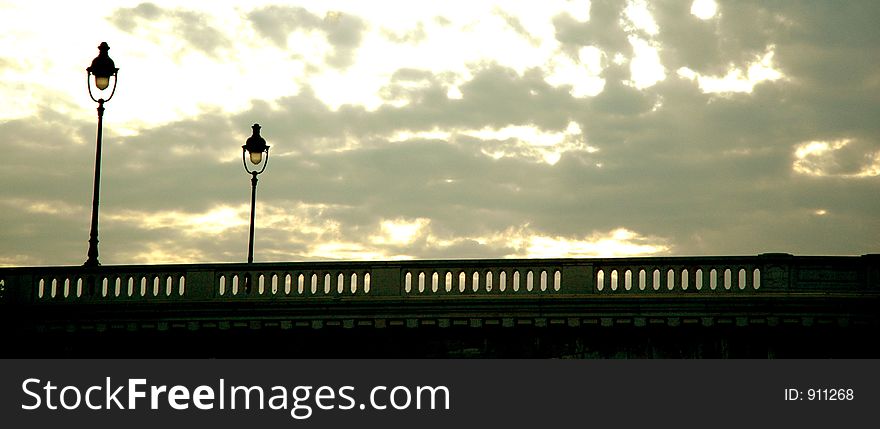 Sunset behind a bridge with two light poles. Sunset behind a bridge with two light poles...