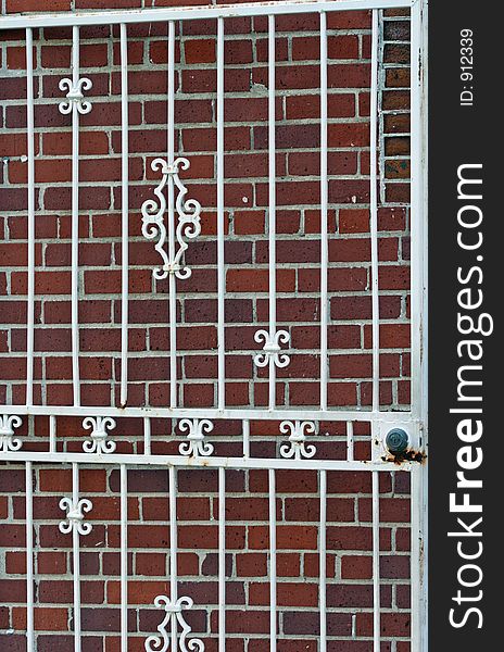 Ornate white iron gate against brick wall. Ornate white iron gate against brick wall