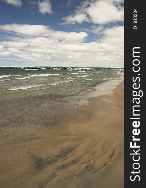 Waves crash along an empty beach on a sunny summer day. Waves crash along an empty beach on a sunny summer day