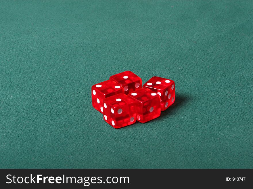 Dices being thrown in a craps game, or yatzee or any kind of dice involved game, Dices are a clear red color on a green felt table. Dices being thrown in a craps game, or yatzee or any kind of dice involved game, Dices are a clear red color on a green felt table