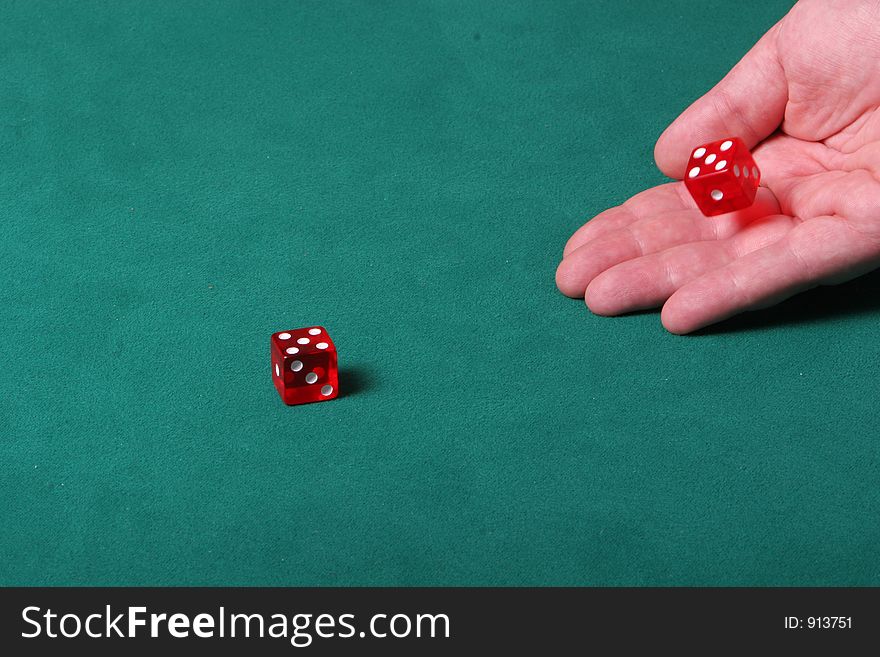Dices being thrown in a craps game, or yatzee or any kind of dice involved game, Dices are a clear red color on a green felt table. Dices being thrown in a craps game, or yatzee or any kind of dice involved game, Dices are a clear red color on a green felt table