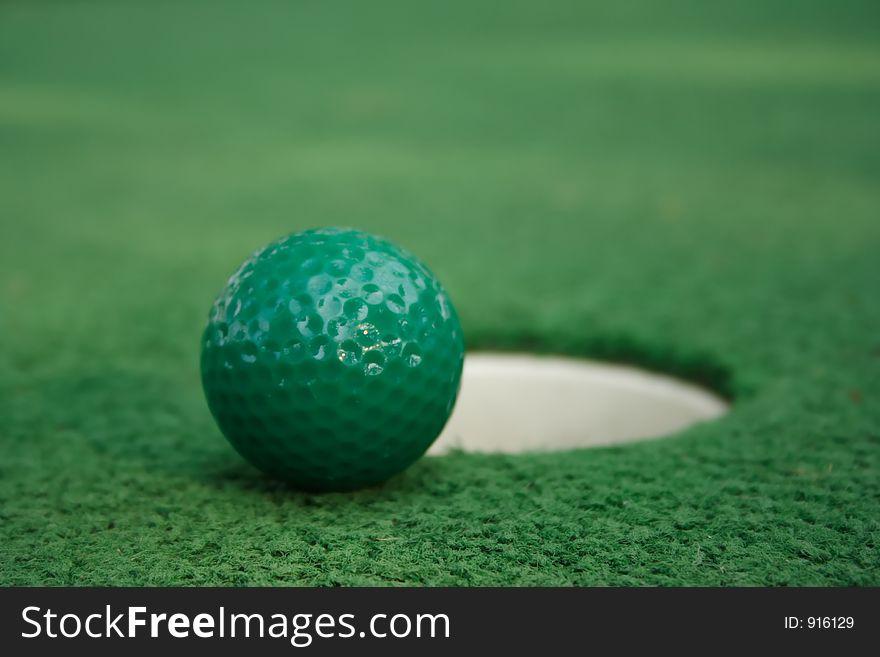 A miniature golf ball near the hole. A miniature golf ball near the hole