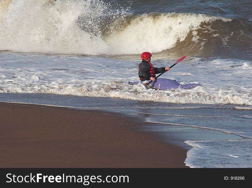 Man in blue canoe, on edge of surf. Man in blue canoe, on edge of surf