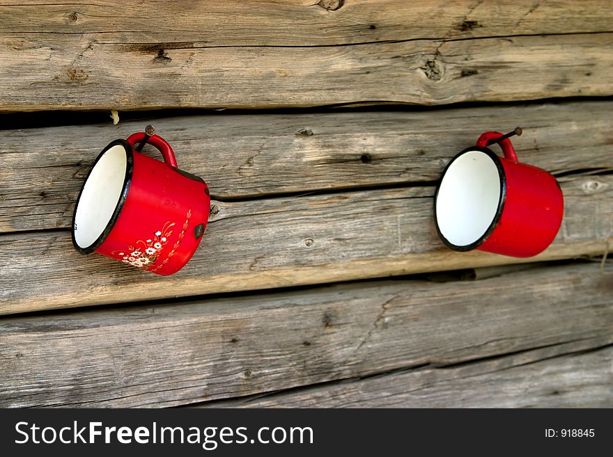 Metal red mugs hanging on the wood wall