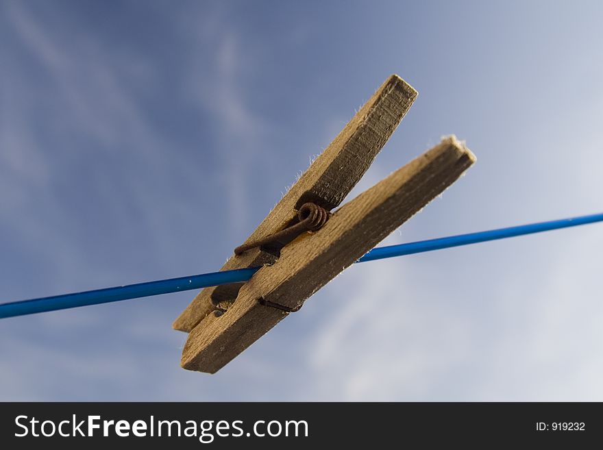 Lonely clothes peg on blue cord of rotary clothes line. Lonely clothes peg on blue cord of rotary clothes line.