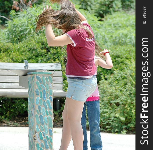 Two girls wetting their hair at a fountian on a hot day. Two girls wetting their hair at a fountian on a hot day.